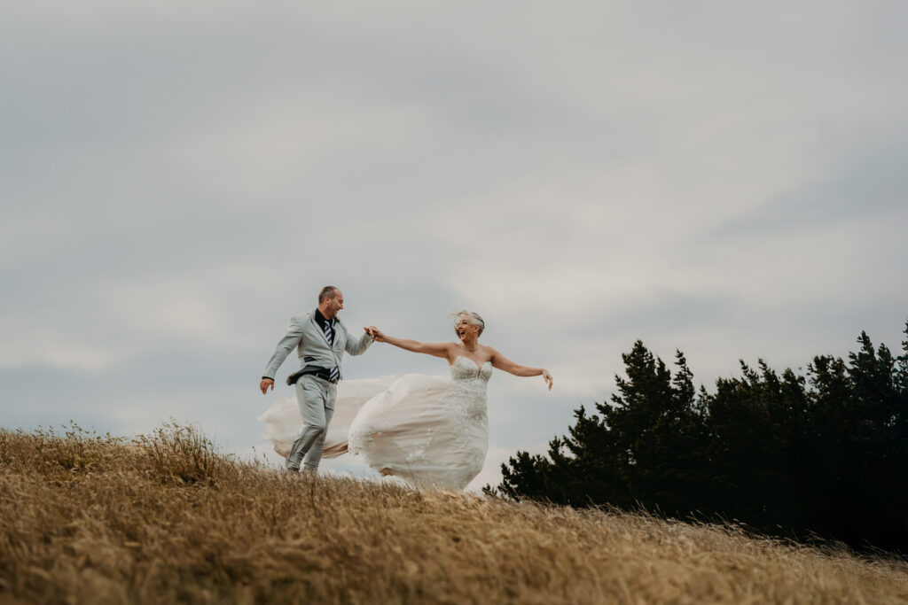 Couple-dance-on-hill-in-strong-winds-at-Waipuna-Estate-wedding-day.jpg